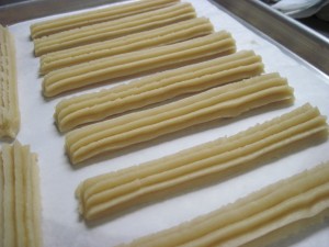 pipe out churro dough onto a paper lined sheet pan