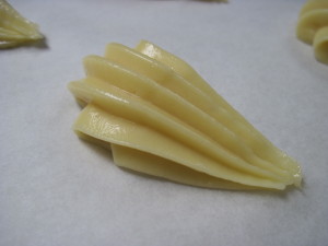 piping out the bodies of eclair swans using a large scalloped decorating tip
